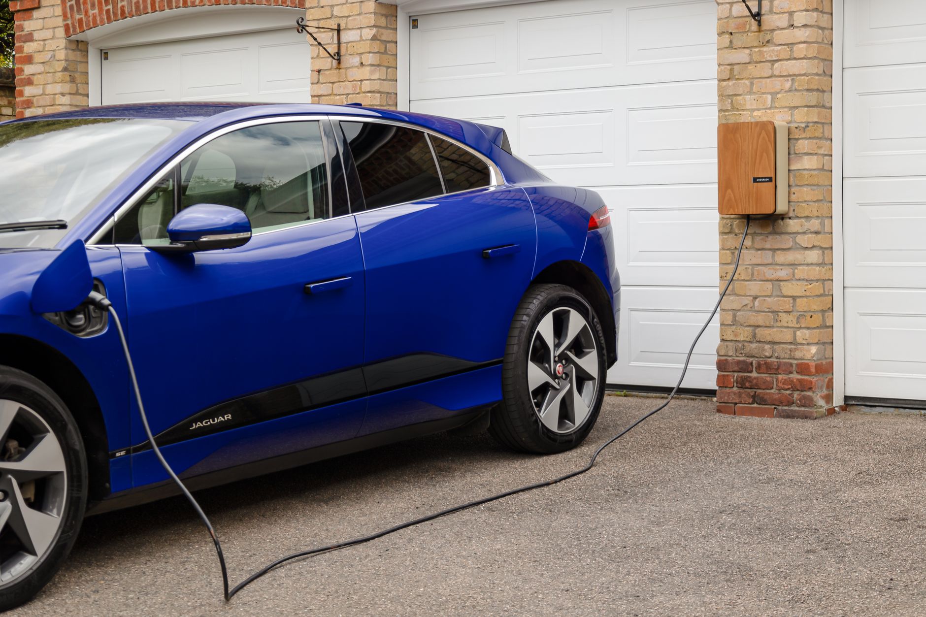 Electric vehicle charging beside a residential garage
